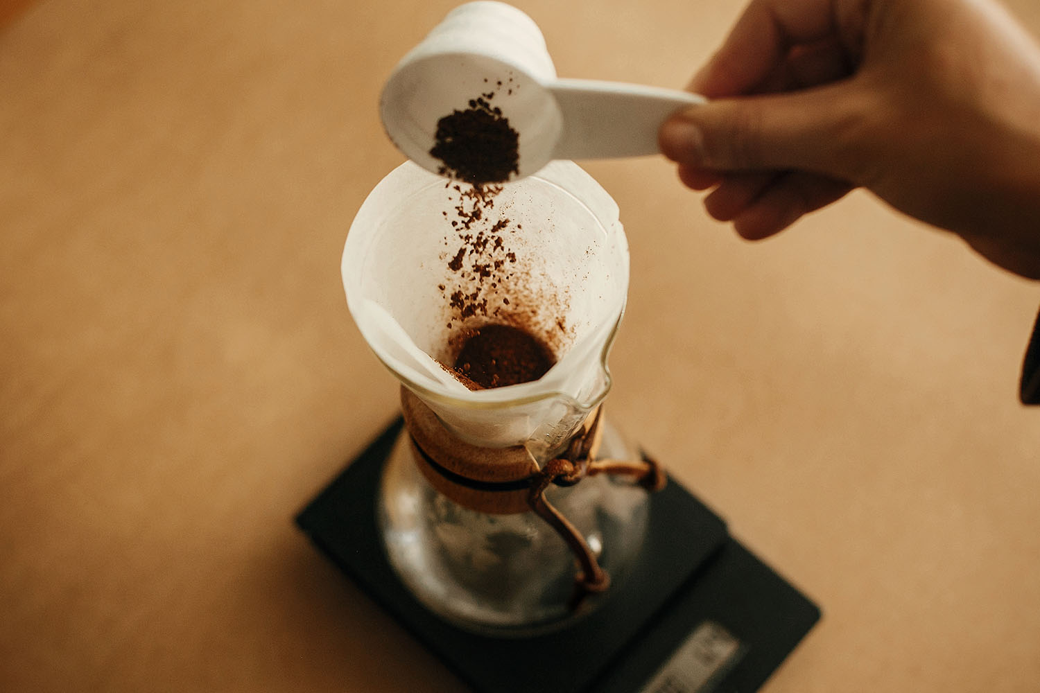 Hands pouring grounded coffee in filter. Preparing for alternati